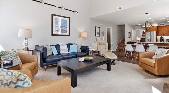 Settle into your spacious open-concept living area, where comfortable seating surrounds a stylish coffee table—perfect for gathering with loved ones. Sunlight streams through, creating a warm, welcoming retreat you'll love coming home to.