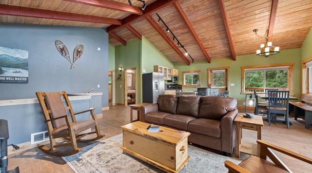Unwind in your open-concept living space with vaulted wood ceilings and natural light. The leather sofa invites you to relax after a day of adventure, while the kitchen and dining area make it easy to gather and share meals together.