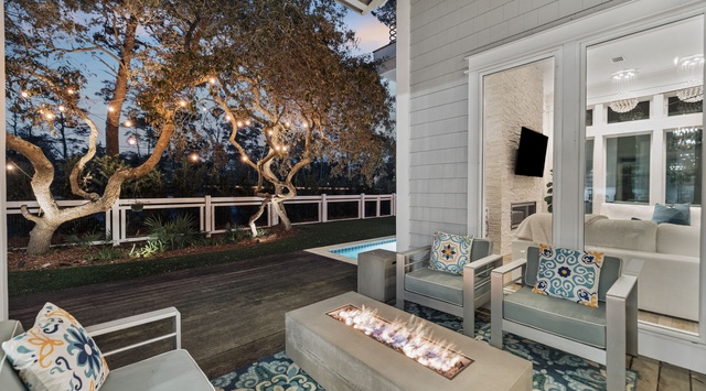 Your evening sanctuary awaits with cozy seating around a fire table, overlooking your private pool and garden.