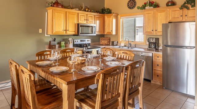 Gather around this welcoming dining table in your fully equipped kitchen, where warm wood tones and modern appliances set the stage for memorable meals together.