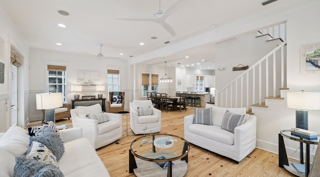 Sink into plush white sofas in your bright, airy living space featuring soaring ceilings and warm wood floors.