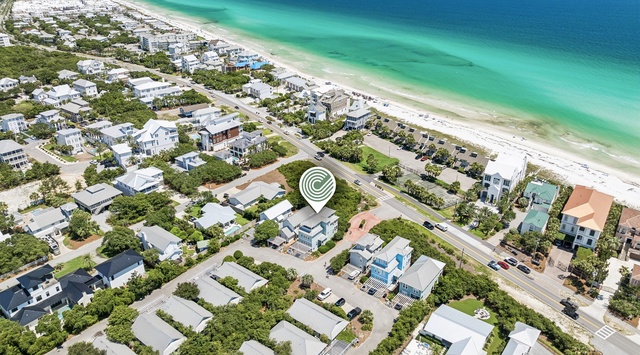 Aerial view showcasing the property's prime beachfront location along pristine white sand shores and stunning turquoise waters, nestled within a peaceful coastal community.