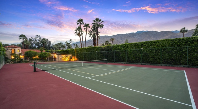 Private tennis court framed by palm trees and mountain views, perfect for an active getaway at this desert retreat.
