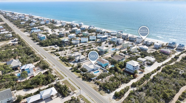 Aerial view of a coastal community with beachfront homes and easy beach access just steps away from pristine white sand shores.