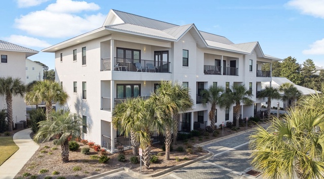 Modern coastal property featuring multiple balconies and tropical landscaping with palm trees in a tranquil neighborhood setting.
