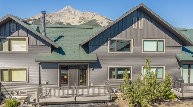 A spacious mountain lodge with dramatic views of Big Sky peak, offering a peaceful retreat surrounded by alpine beauty and natural landscaping.
