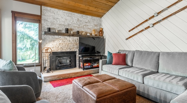 Curl up by the fireplace in this cozy living room with vaulted wood ceilings, plush seating, and charming mountain-cabin decor perfect for relaxing after your adventures.