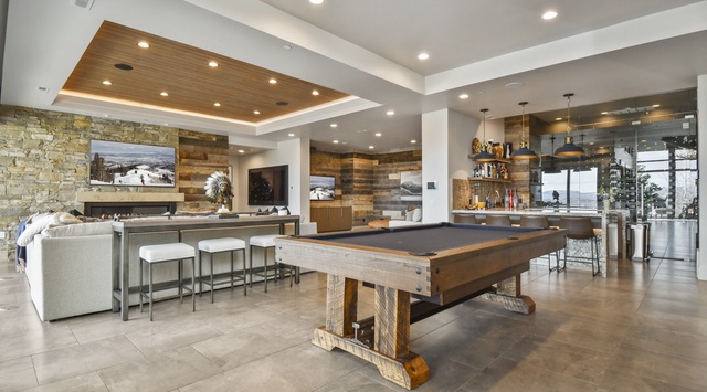 Your luxury living space features a stunning billiard table, cozy fireplace, and open kitchen—perfect for memorable evenings with friends and family.