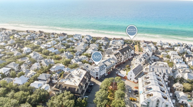 Aerial view of a charming beachside community with pristine white sand beaches and turquoise waters just steps away.