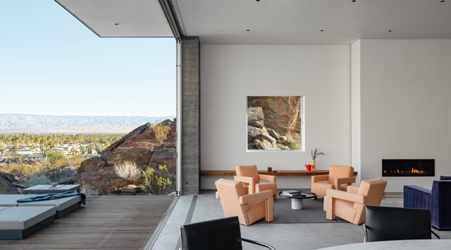 Relax in your modern living space with floor-to-ceiling windows framing stunning mountain views and a cozy fireplace for evening ambiance.