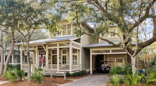 Charming coastal-style home nestled among mature trees with welcoming front porch and convenient covered parking for your arrival.