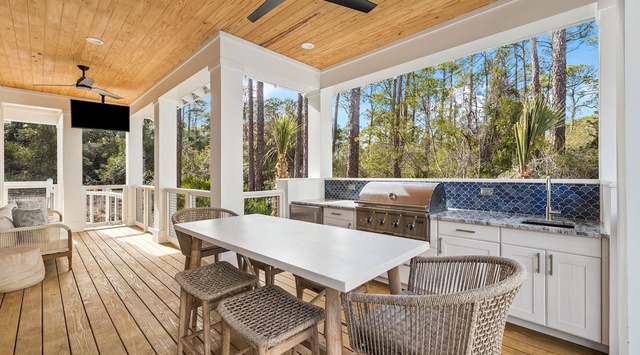 Your covered porch dining area features a stunning outdoor kitchen perfect for cooking while enjoying forest views.