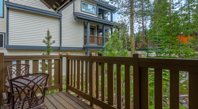 A charming balcony nestled among towering pines, featuring a cozy café-style seating set surrounded by lush forest views, perfect for your morning coffee or evening retreat.