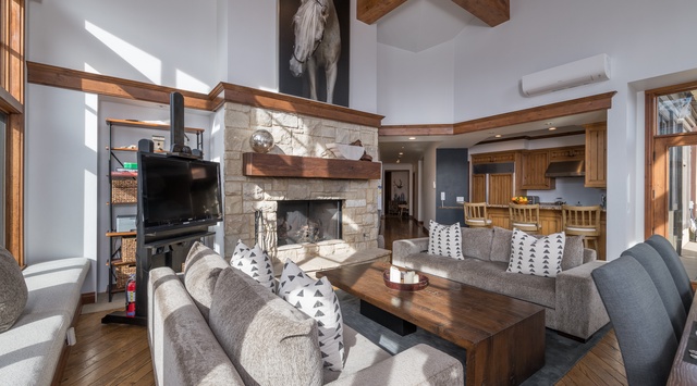 Unwind in your spacious living room featuring a stunning stone fireplace, exposed beams, and plush seating perfect for cozy evenings.