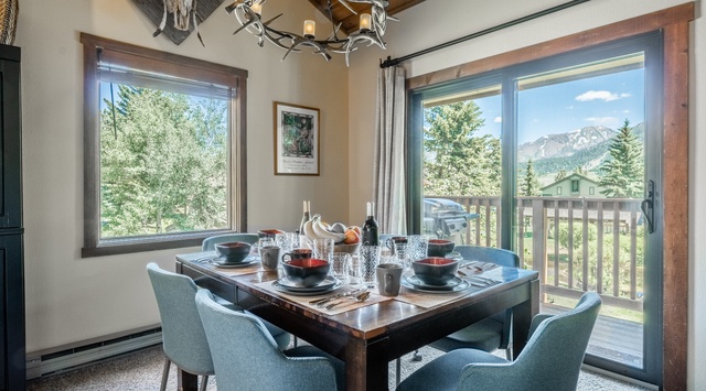 Picture yourself savoring morning coffee at this welcoming dining table, framed by breathtaking mountain vistas. The rustic antler chandelier and cozy alpine touches create the perfect setting for memorable meals with loved ones.