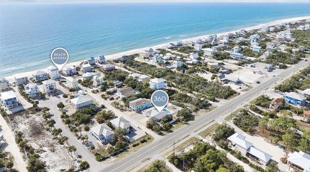 Aerial view of beachfront vacation rental community with pristine white sand beach and turquoise waters nearby.