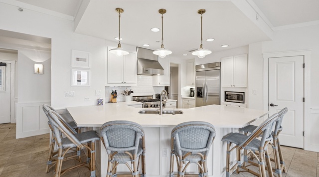 Gather around this spacious kitchen island with seating for six, where gleaming white cabinetry, stainless appliances, and warm pendant lighting create the perfect spot for your morning coffee or evening meal prep.