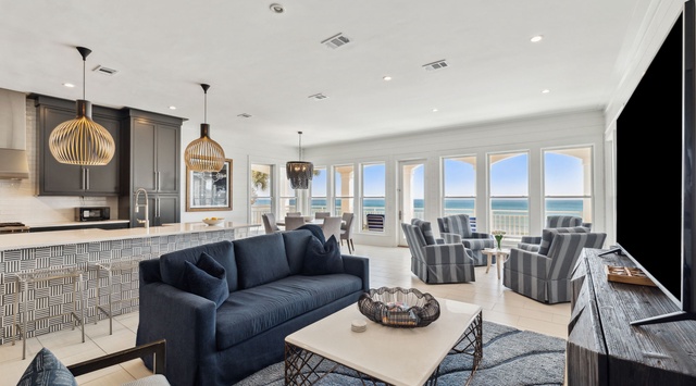 Stunning ocean views frame your living space, where the open-concept design flows seamlessly from the gourmet kitchen to a cozy living area with plush seating—perfect for gathering after a beach day.