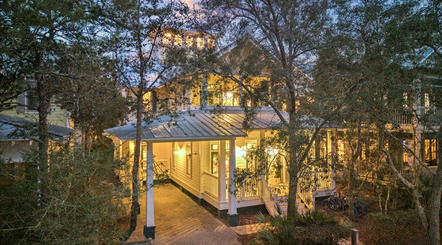 Beautiful property nestled among mature trees with warm lighting creating an inviting evening atmosphere in the peaceful neighborhood setting.
