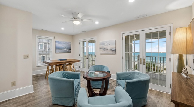 Step into your bright coastal retreat where plush seating invites you to unwind and stunning ocean views await just beyond the French doors. Soft lighting and beachy tones create the perfect seaside escape.