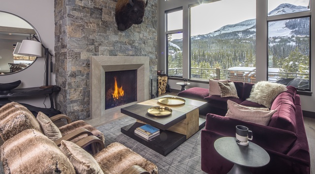 Sink into plush velvet seating beside a crackling stone fireplace while you take in sweeping mountain views through floor-to-ceiling windows—a perfect blend of cozy warmth and alpine grandeur.