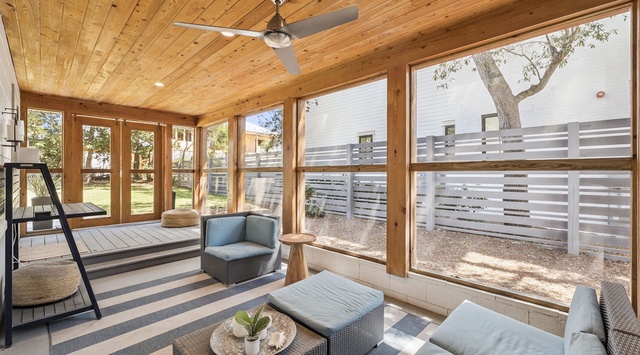 Relax in your private screened porch with comfortable seating and natural light streaming through large windows.