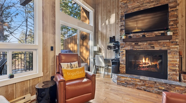 Curl up in your cozy leather chair by the crackling fireplace, watching flames dance while sunlight streams through tall windows.