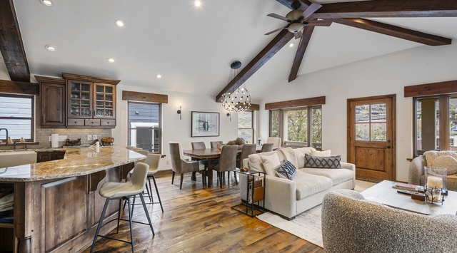 Step into your inviting open-plan retreat with soaring cathedral ceilings, warm wood beams, and abundant natural light. The spacious living area flows seamlessly into a chef's kitchen and dining space, perfect for memorable gatherings.