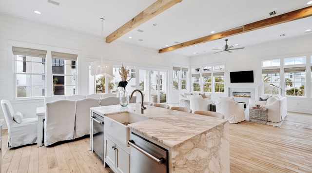 Your stunning open-concept kitchen flows seamlessly into the living area, featuring gleaming marble countertops and rustic wood beams overhead.