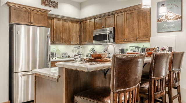 Your fully equipped kitchen invites you to gather and cook comfortably, featuring rich wood cabinetry, modern stainless appliances, and a spacious island with seating for everyone.