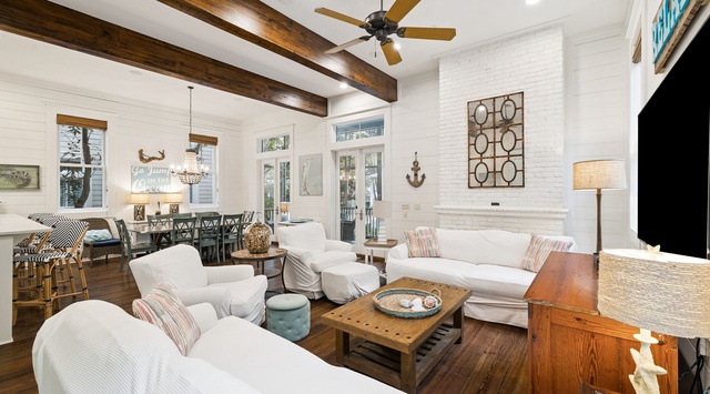 Relax in your bright, airy living room with exposed beams, coastal decor, and comfortable seating perfect for unwinding.