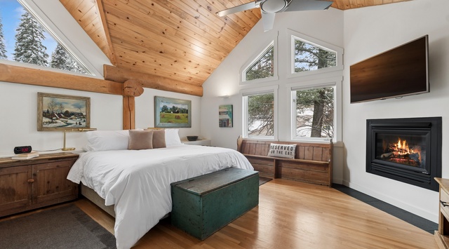 Cozy up in your mountain bedroom with crackling fireplace, soaring wood ceilings, and peaceful forest views through expansive windows.