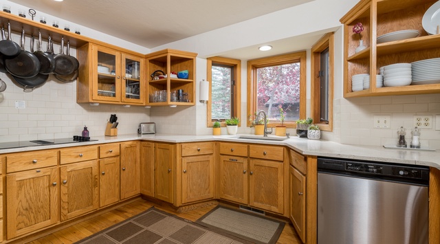 Your spacious kitchen awaits with warm wood cabinetry, ample counter space, and modern appliances. Natural light streams through the windows, illuminating a welcoming space where you can prepare meals and gather comfortably.
