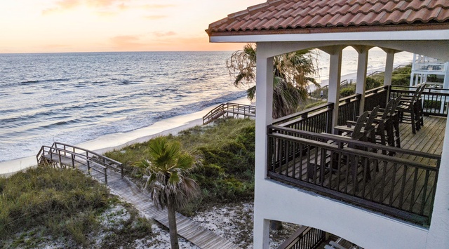 This beachfront property offers direct access to sandy shores and stunning ocean views, with tiered balconies overlooking palm-studded dunes and a scenic boardwalk leading to the water's edge.