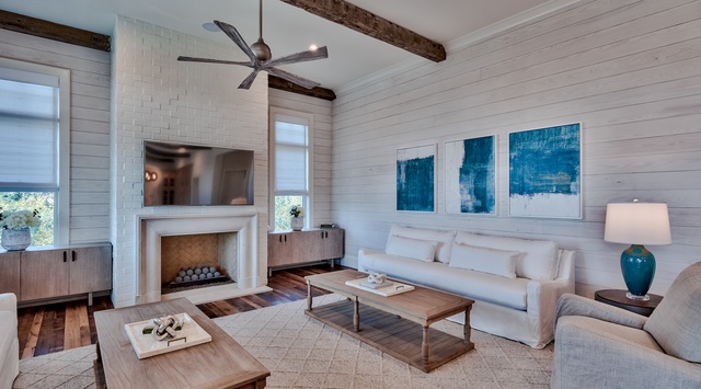 Unwind in your sophisticated living room featuring white shiplap walls, exposed beams, and a cozy fireplace perfect for evening relaxation.