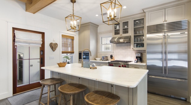 Gourmet kitchen with gleaming marble countertops, professional-grade appliances, rustic wood beams, and a spacious island perfect for meal prep and gathering.