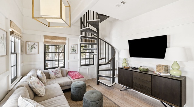 Curl up in this stylish living space featuring a plush sectional sofa and modern spiral staircase.