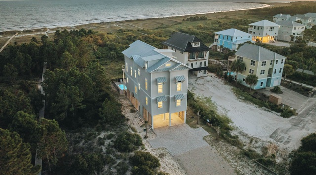 Coastal neighborhood at sunset featuring beachfront properties with direct beach access and serene ocean backdrop.