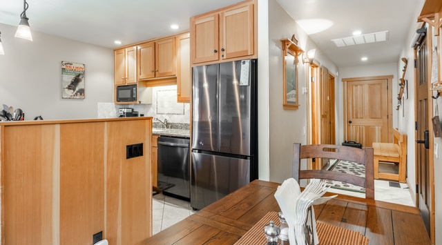 Your fully equipped kitchen awaits with warm wood cabinetry, stainless steel appliances, and an inviting dining table perfect for gathering over home-cooked meals or morning coffee.