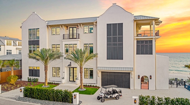 Modern beachfront property with stunning ocean views, featuring elegant architecture and prime coastal location with dramatic sunset skies.