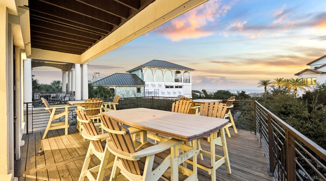 Spacious deck with dining table overlooks coastal neighborhood during golden hour.