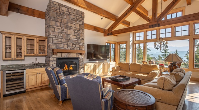 Gather in this stunning great room with soaring timber-frame ceilings, a cozy stone fireplace, and expansive windows framing breathtaking ocean views—your ideal retreat for relaxation and connection.