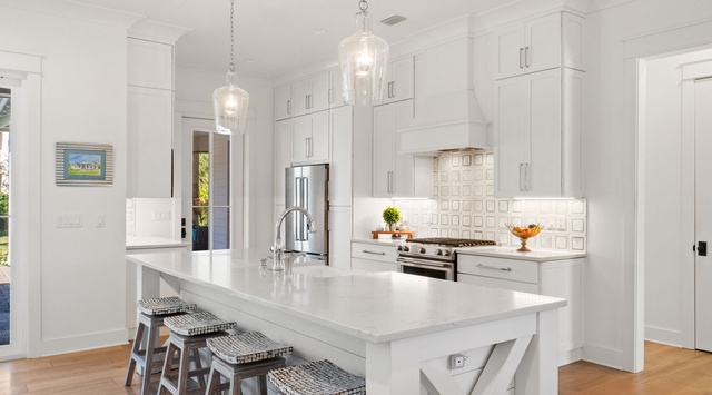 Your bright, modern kitchen features pristine white cabinetry, elegant pendant lighting, and a spacious island perfect for morning coffee or meal prep.