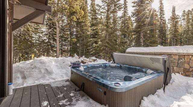 Soak in your private hot tub surrounded by snow-covered pines and golden winter sunlight filtering through the forest.