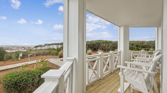 Relax on your private balcony with white rocking chairs, overlooking coastal dunes and natural vegetation, just steps from the beach.