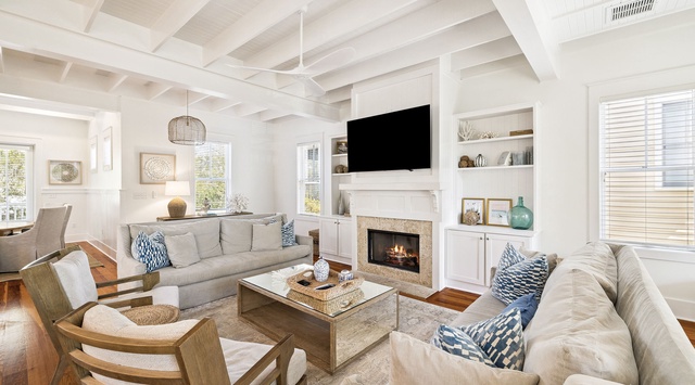 Relax in your spacious living room featuring plush seating, a cozy fireplace, and coastal-inspired decor that invites peaceful moments.