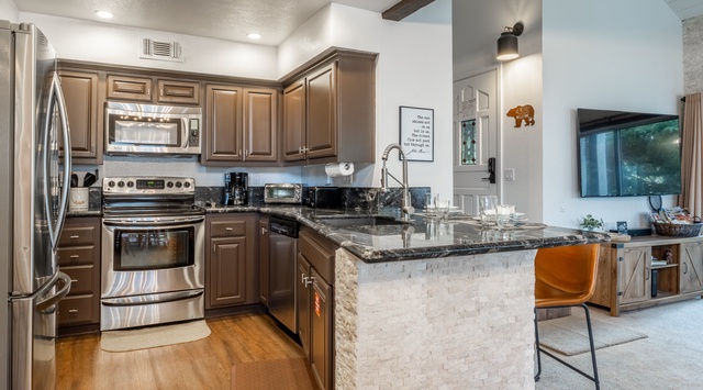 Your fully-equipped kitchen features rich cabinetry, granite countertops, and stainless steel appliances—perfect for preparing meals or enjoying morning coffee at the breakfast bar.
