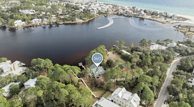 Stunning aerial view of the property nestled between tranquil bay waters and pristine coastline, surrounded by lush vegetation in a peaceful residential area.