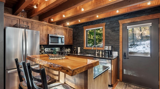 Your rustic-modern kitchen blends warm wood beams with sleek stainless appliances, perfect for cooking mountain meals.