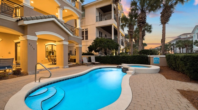 Stunning vacation home with private pool and spa surrounded by tropical palms at sunset.